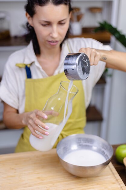 Woman pouring almond milk in glass bottle