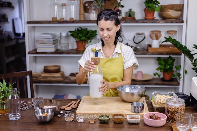 Woman pouring almond milk in glass bottle