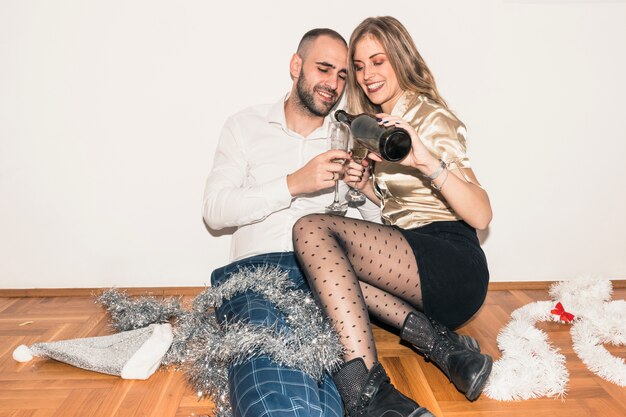 Woman pouring champagne in glass of man