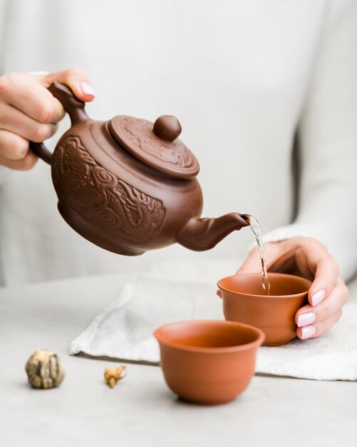 Woman pouring cup of tea with teapot