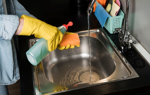 Woman pouring detergent in sponge to clean the sink