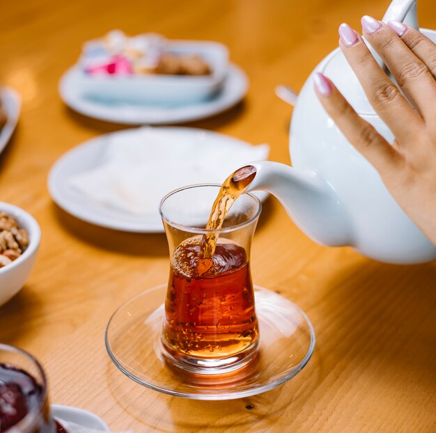 Woman pouring tea in armudy glass side view