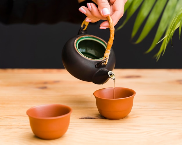 Женщина наливает чай в глиняную чашку