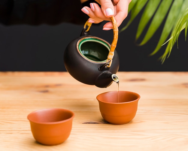 Woman pouring tea in clay cup