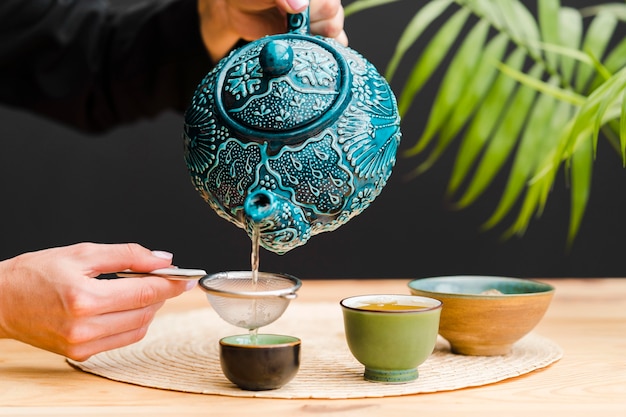 Woman pouring tea in cup through sieve