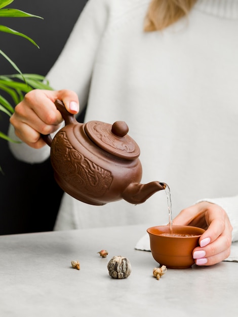 Woman pouring tea from clay teapot