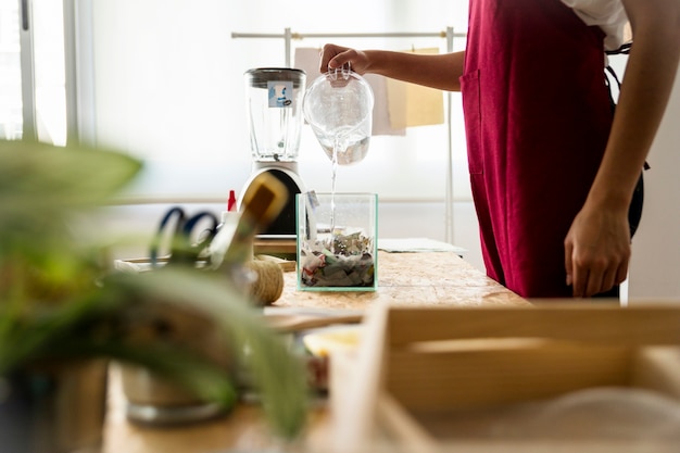 Woman pouring water in container filled with torned papers