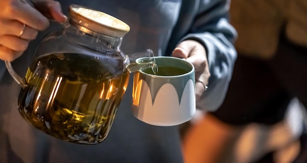 Free photo a woman pours tea into a cup late at night