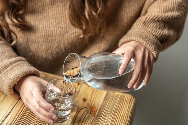 女性がガラスデカンターからガラスに水を注ぐ