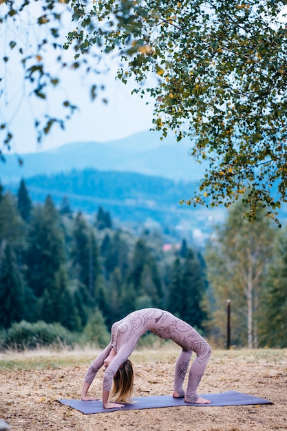 A woman practices yoga at the morning in a park on a fresh air.