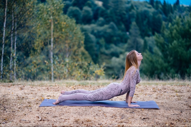 A woman practices yoga at the morning in a park on a fresh air.