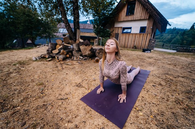 A woman practices yoga at the morning in a park on a fresh air.