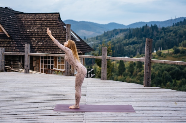 Free photo a woman practices yoga at the morning in a terrace on a fresh air.