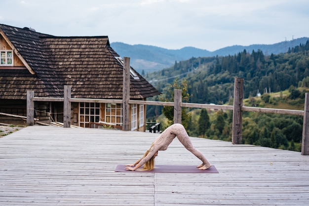 A woman practices yoga at the morning in a terrace on a fresh air.