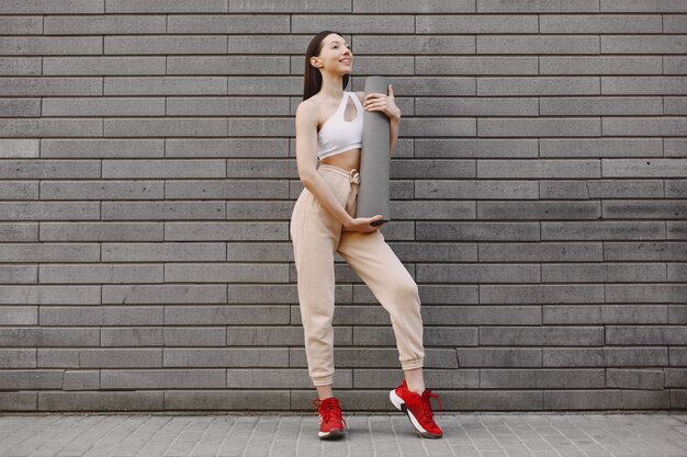 Woman practicing advanced yoga against a dark urban wall