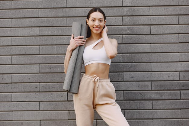 Woman practicing advanced yoga against a dark urban wall