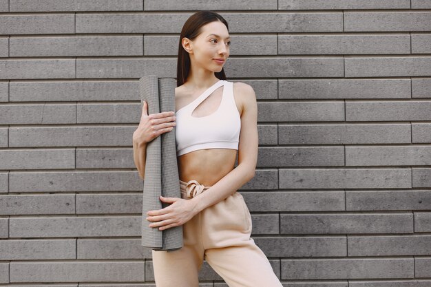 Woman practicing advanced yoga against a dark urban wall