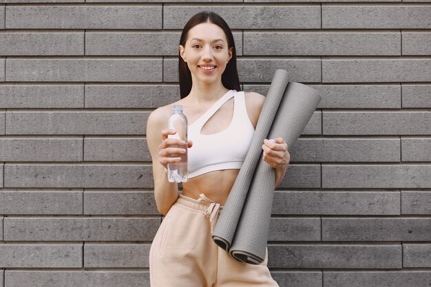 Woman practicing advanced yoga against a dark urban wall