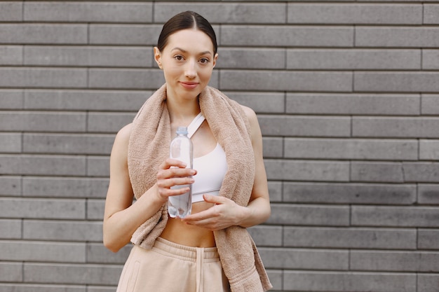 Woman practicing advanced yoga against a dark urban wall