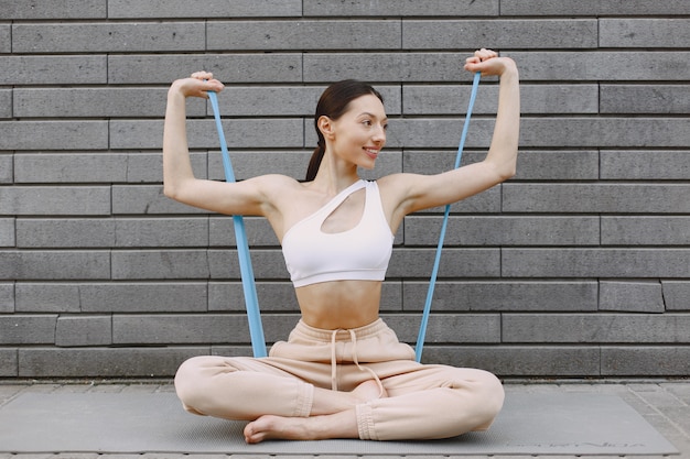 Woman practicing advanced yoga against a dark urban wall