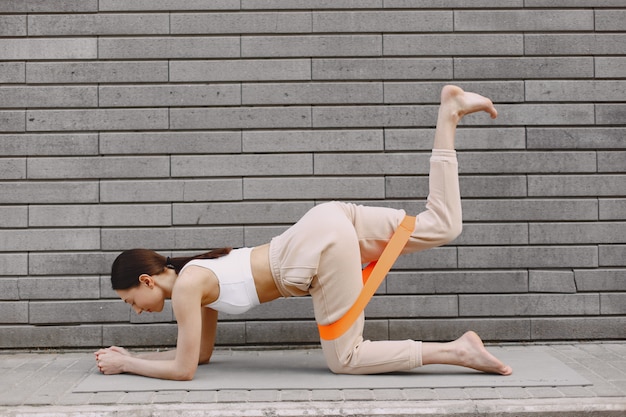 Woman practicing advanced yoga against a dark urban wall