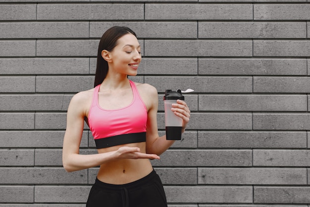 Woman practicing advanced yoga against a dark urban wall