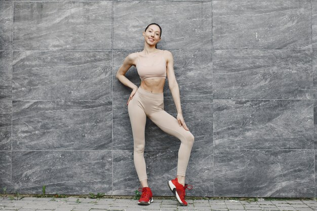 Woman practicing advanced yoga against a dark urban wall