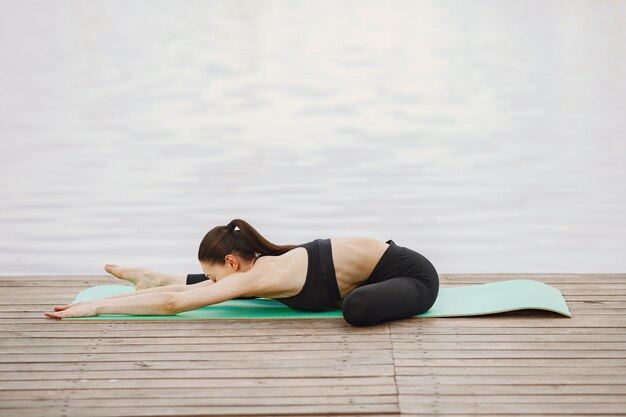 Woman practicing advanced yoga by the water