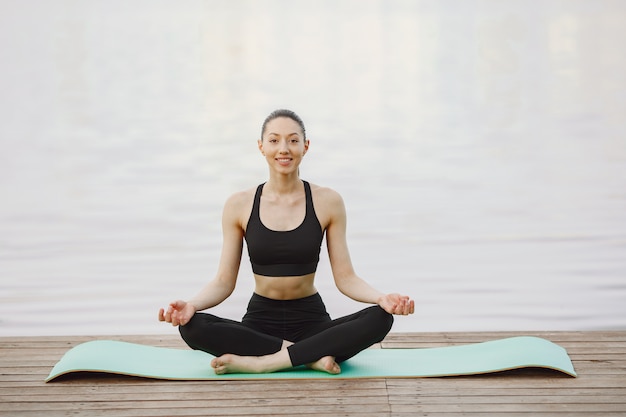 Free photo woman practicing advanced yoga by the water