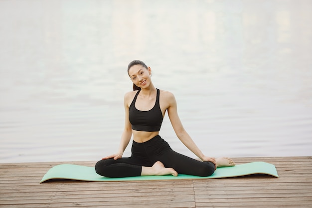 Woman practicing advanced yoga by the water