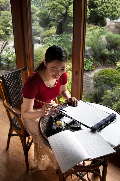 Foto gratuita donna che pratica la scrittura giapponese al chiuso