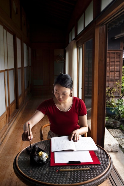 Free photo woman practicing japanese handwriting indoors