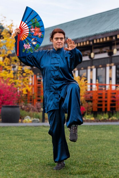 woman practicing tai chi outdoors full shot