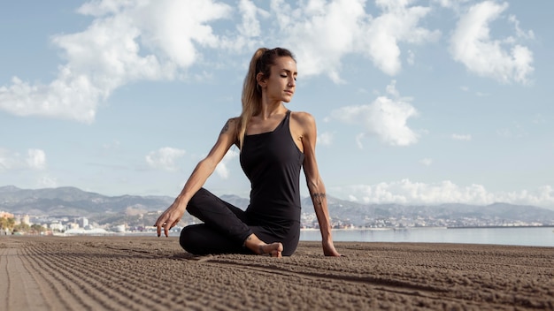 Woman practicing yoga on the beach sand