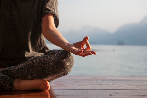 Free photo woman practicing yoga by a lake