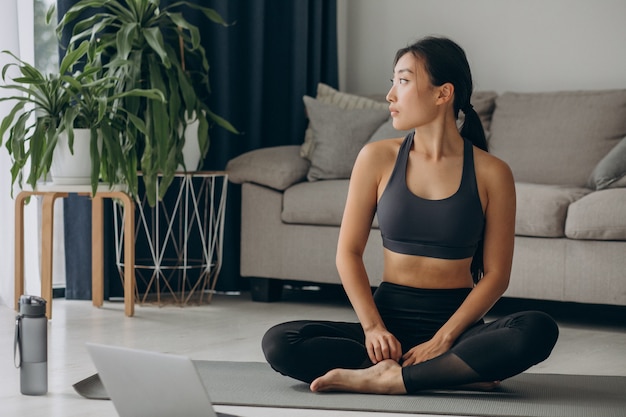 Woman practicing yoga on mat at home