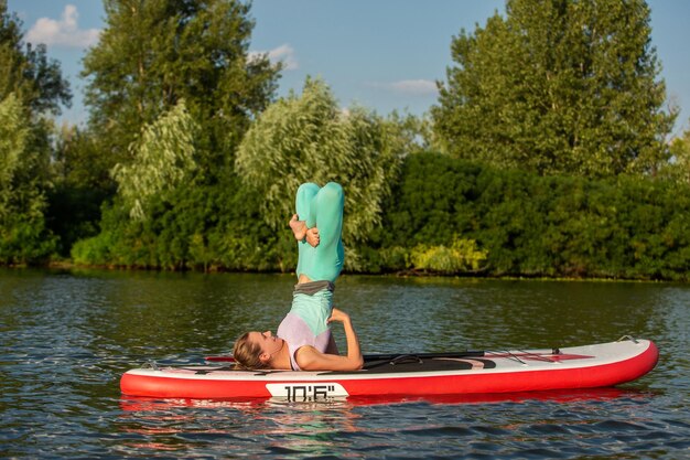 Woman practicing yoga on the paddle board in the morning. Sport. Hobby. Yoga.