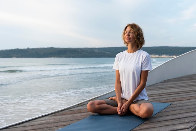 Woman practicing yoga pose near sea
