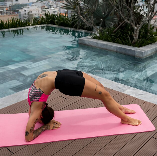 Woman practicing yoga position outdoors by the pool