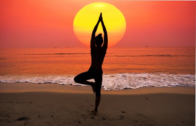 Woman practicing yoga with the sun behind her