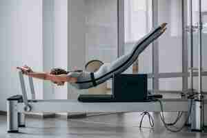 Free photo woman practising pilates in a pilates reformer