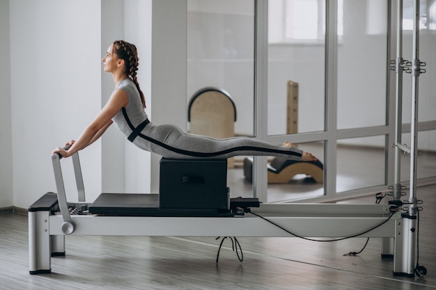 Foto gratuita pilates di pratica della donna in un riformatore dei pilates