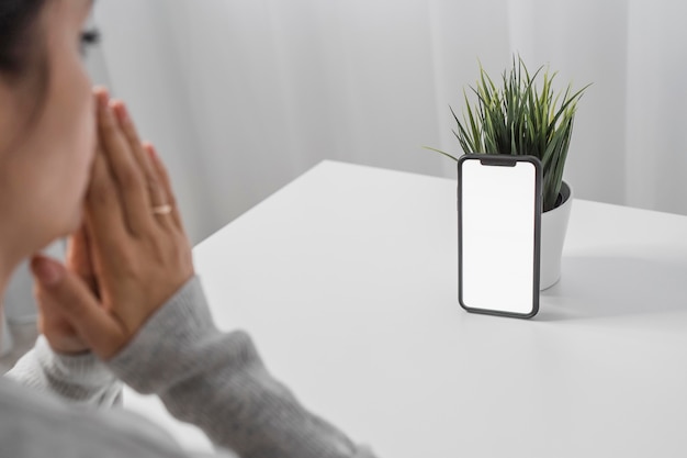 Woman praying with smartphone at home