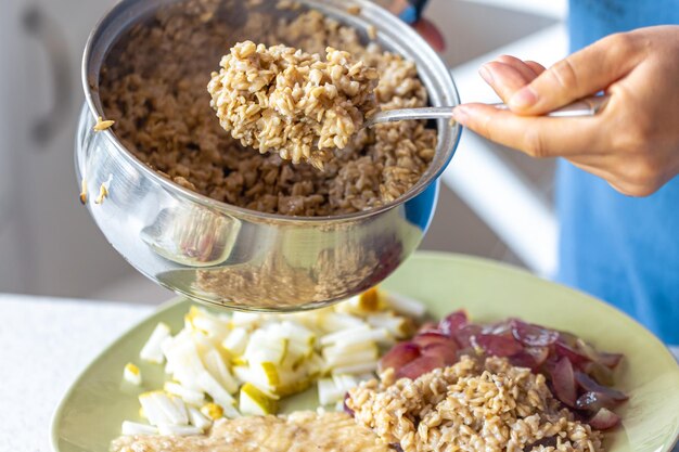 Free photo a woman prepares oatmeal with fruits closeup