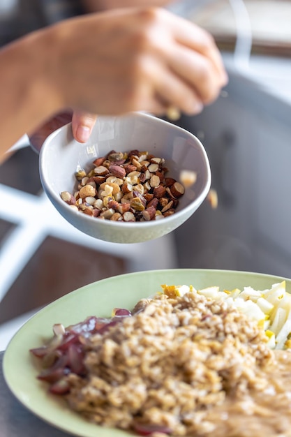 Free photo a woman prepares oatmeal with fruits closeup