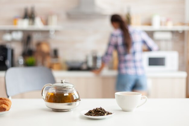 Женщина готовит завтрак на кухне и ароматные травы для горячего чая