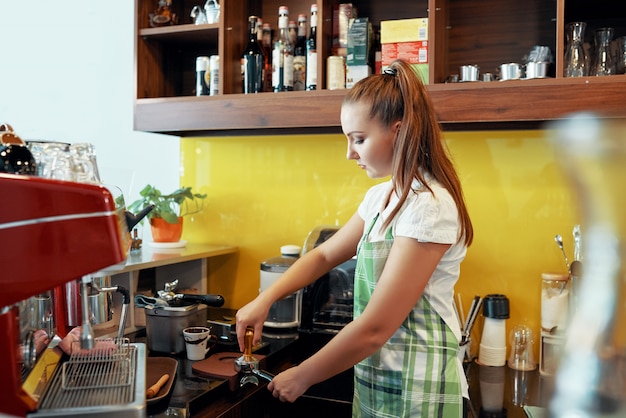 タンパーでコーヒーを準備する女性