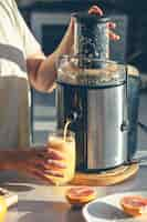 Foto gratuita donna che prepara il succo d'arancia fresco per la colazione in cucina