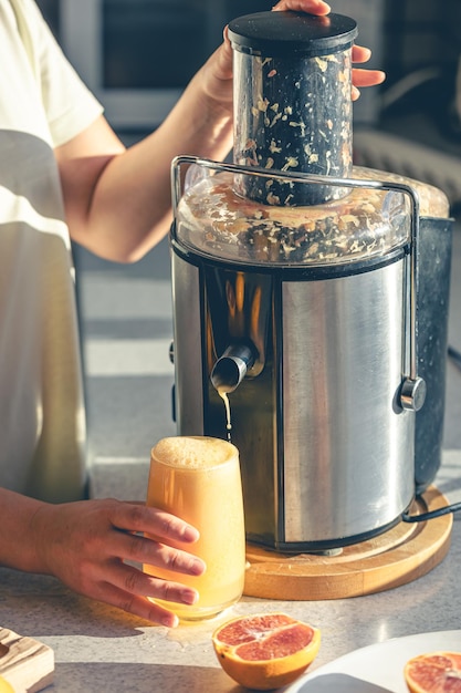 Free photo woman preparing fresh orange juice for breakfast in kitchen