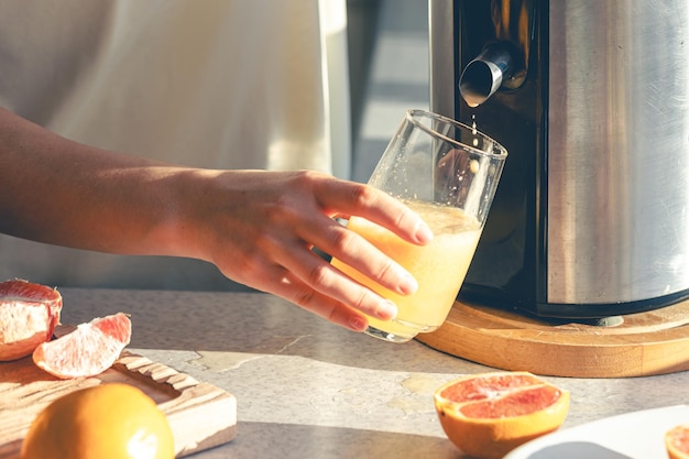 無料写真 キッチンで朝食のために新鮮なオレンジジュースを準備している女性